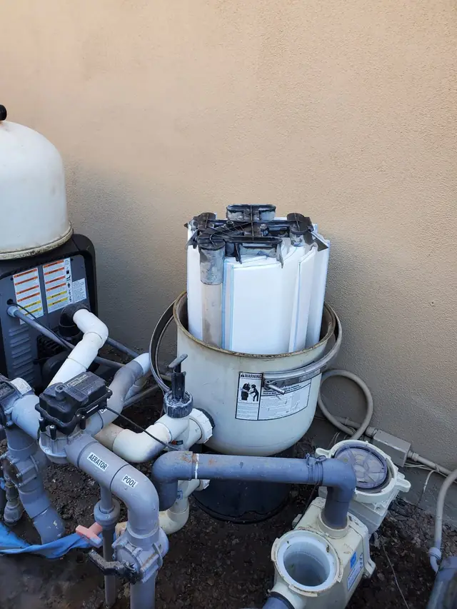 Pool equipment pad with a filter tank, pumps and valves against a block wall